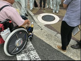 車いすユーザーなどが横断歩道と歩道の段差をチェックしている写真